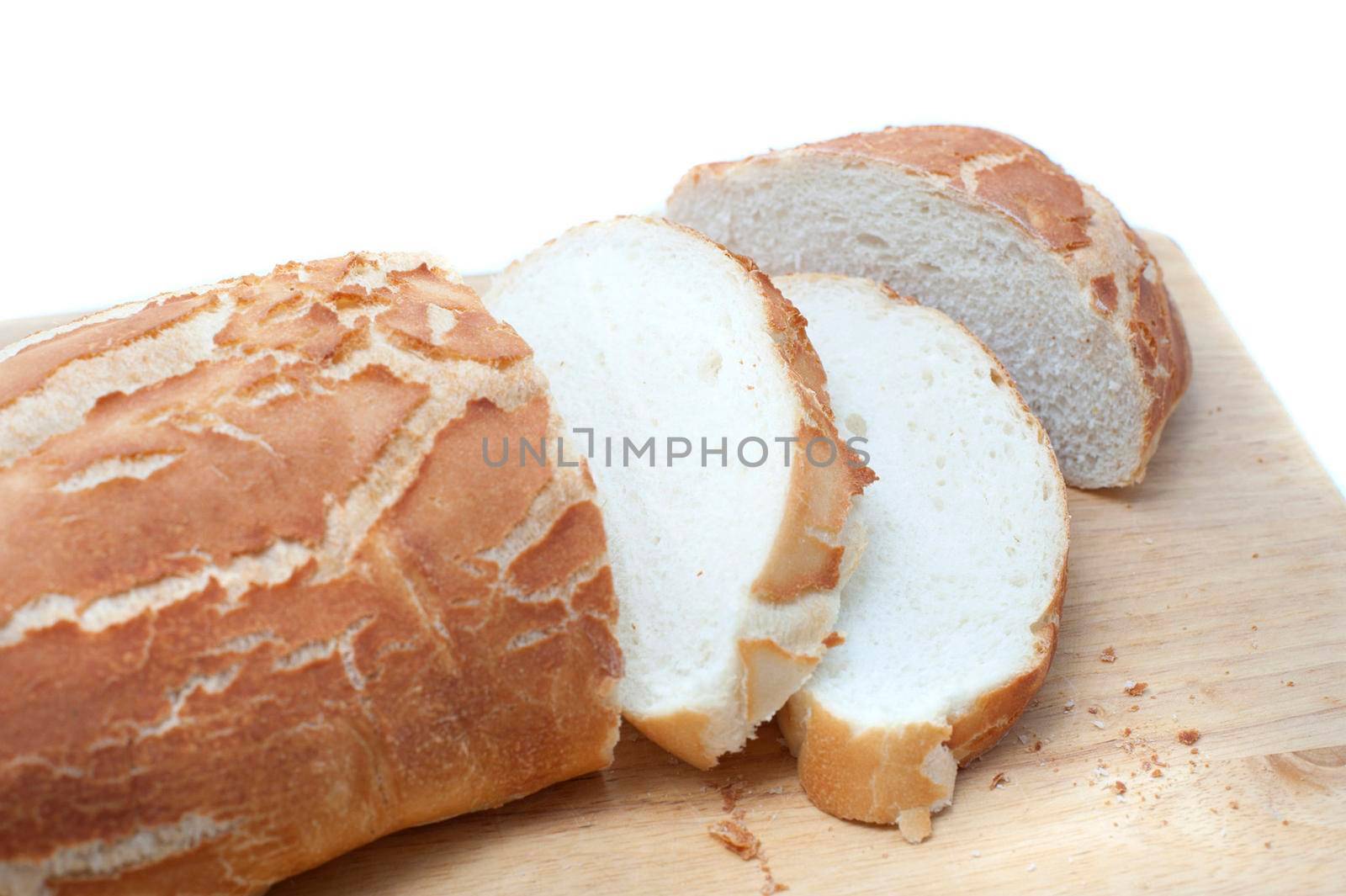 Sliced crispy freshly baked white bread baguette or roll on a bread board, close up view over white with copyspace