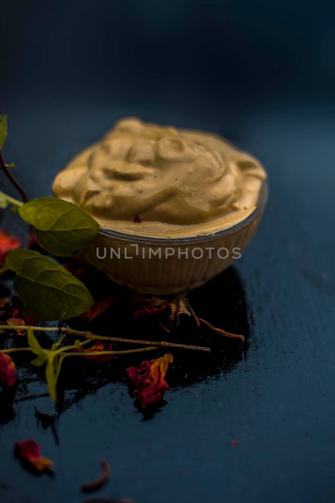 Homemade DIY face mask on the wooden surface consisting of yogurt,multani mitti or mulpani mitti (fuller's earth) and mint leaves in a glass bowl. For the treatment removal of dark patches. by mirzamlk