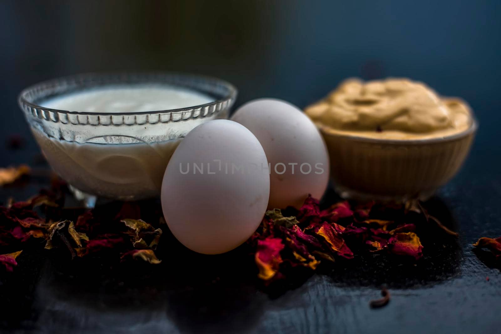 Best DIY face mask of multani mitti or mulpani mitti along with egg white and some yogurt well mixed in a glass bowl on the black wooden surface for the remedy of even skin. by mirzamlk