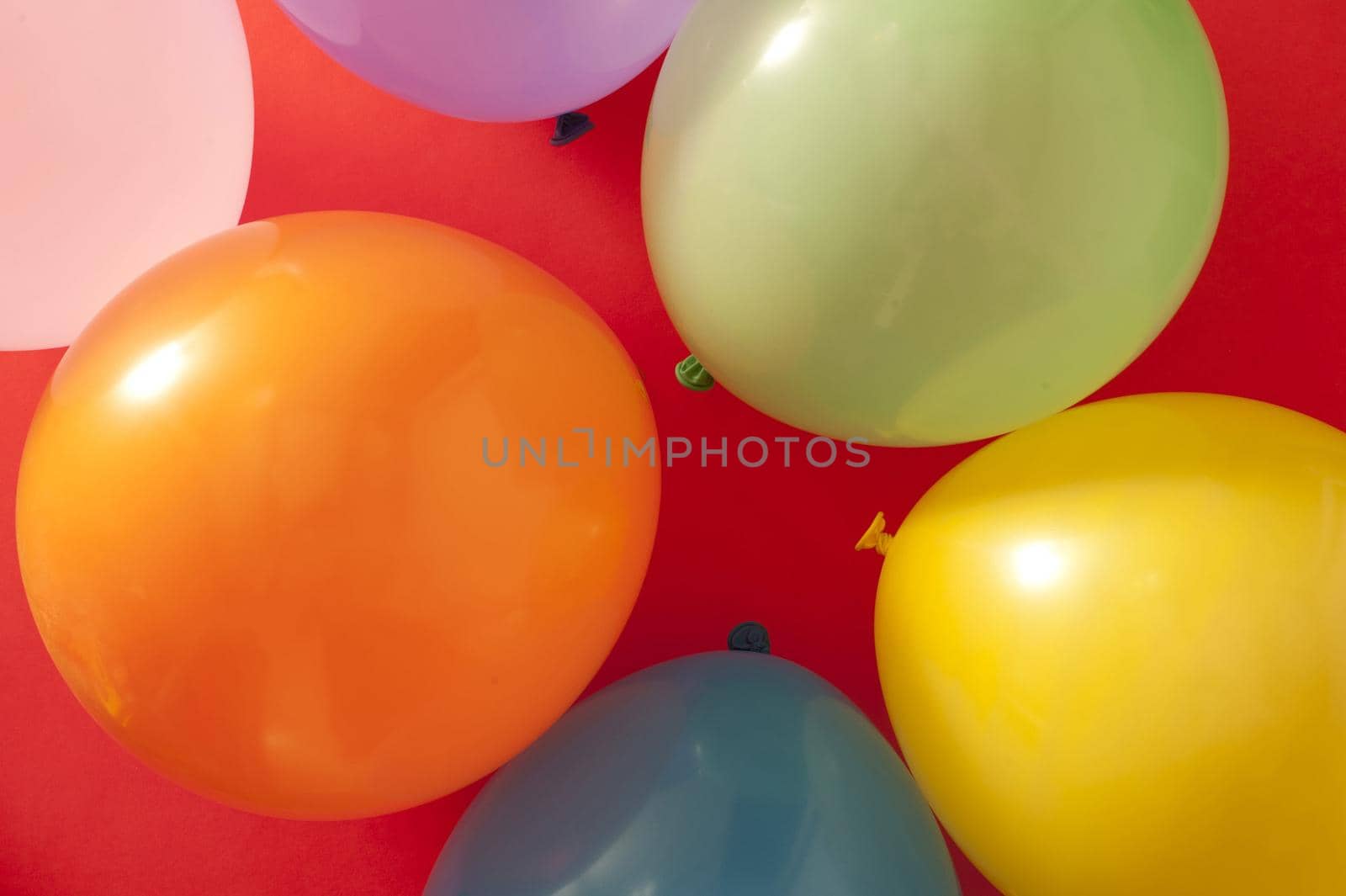 Full frame overhead background of colorful party balloons on red for a festive theme