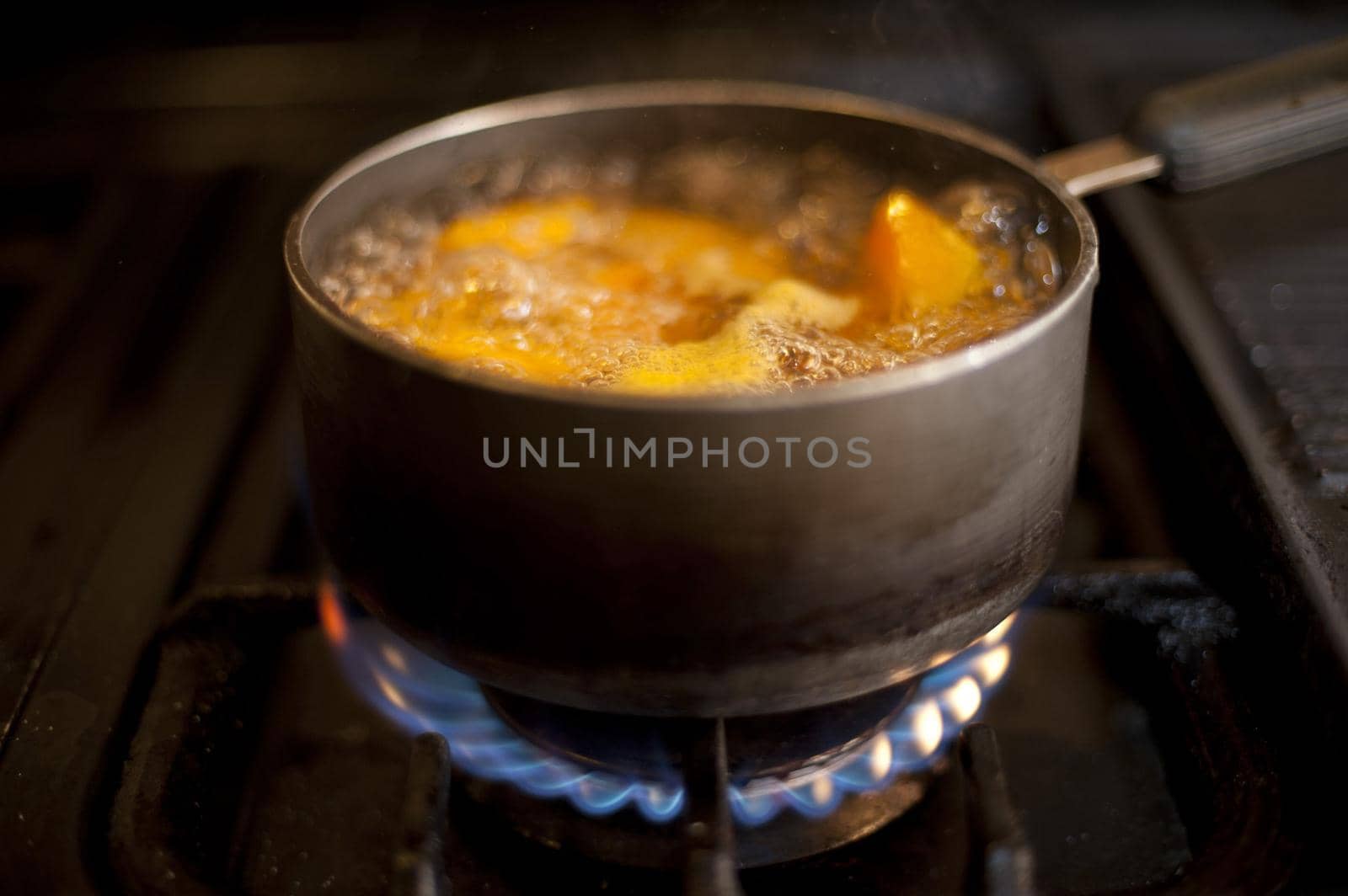 Pumpkin pieces boiling in a saucepan on a gas stove with lots of frothy bubbles