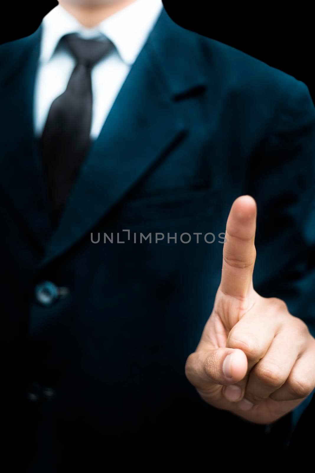 Young businessman or entrepreneur wearing a blue blazer with black necktie expressing as touching something or indicating it isolated on black background.Vertical shot.