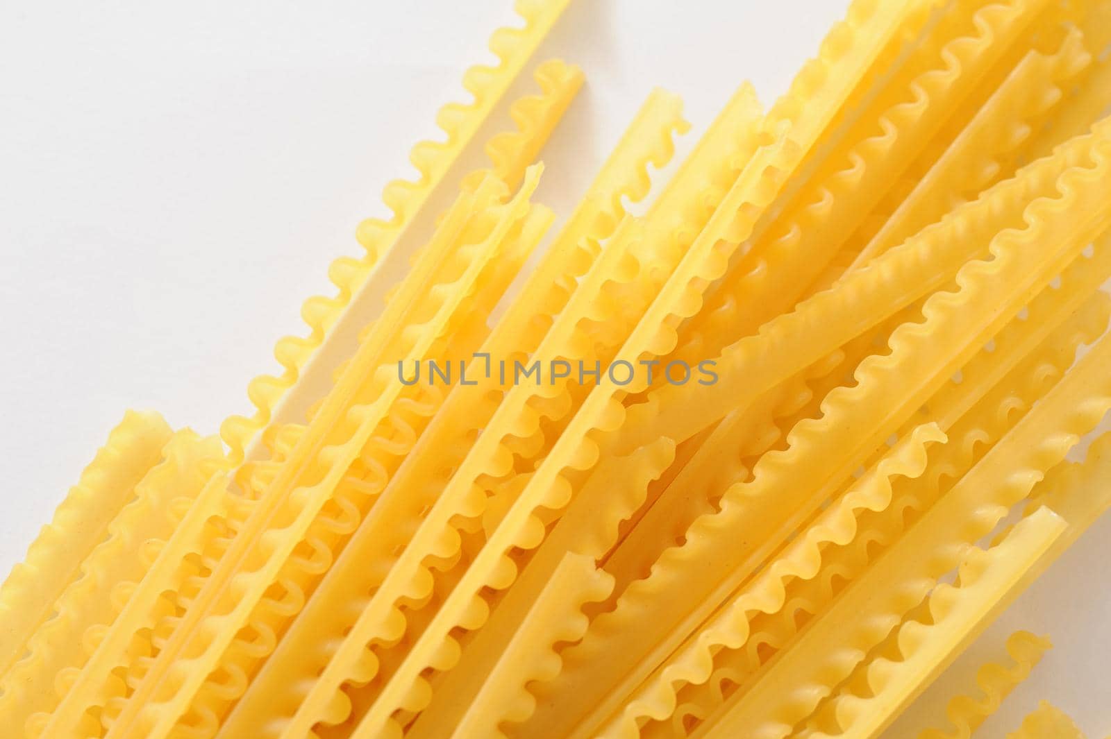 Dried reginette Italian pasta with its frilled wavy edges on a white background, overhead view with copyspace