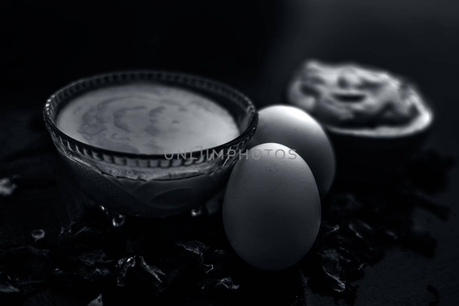 Best DIY face mask of multani mitti or mulpani mitti along with egg white and some yogurt well mixed in a glass bowl on the black wooden surface for the remedy of even skin.