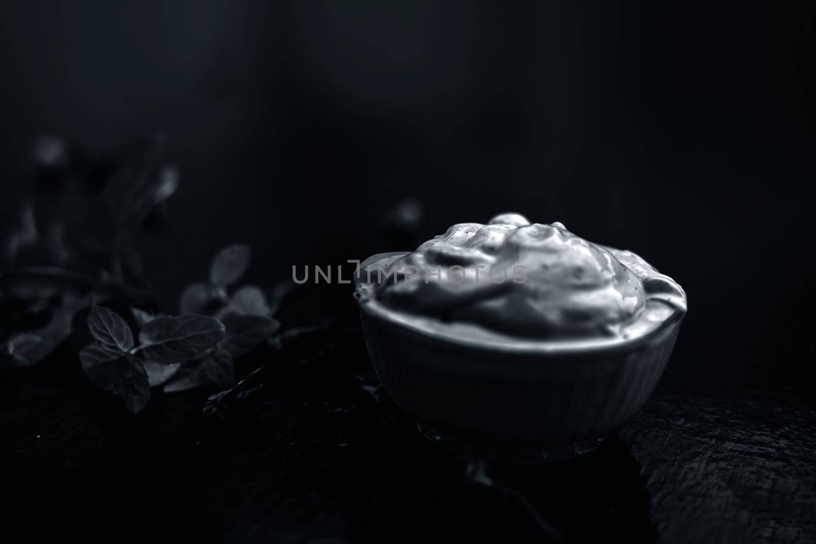 Homemade DIY face mask on the wooden surface consisting of yogurt,multani mitti or mulpani mitti (fuller's earth) and mint leaves in a glass bowl. For the treatment removal of dark patches.