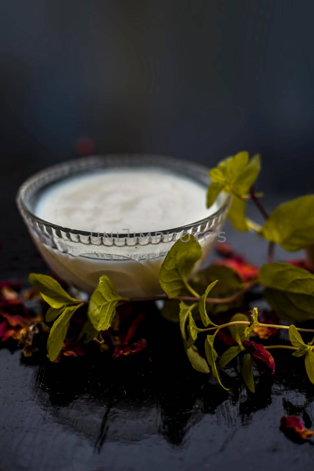 Homemade DIY face mask on the wooden surface consisting of yogurt,multani mitti or mulpani mitti (fuller's earth) and mint leaves in a glass bowl. For the treatment removal of dark patches. by mirzamlk