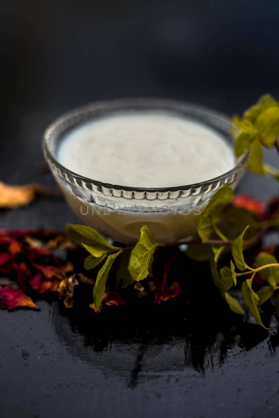 Homemade DIY face mask on the wooden surface consisting of yogurt,multani mitti or mulpani mitti (fuller's earth) and mint leaves in a glass bowl. For the treatment removal of dark patches. by mirzamlk