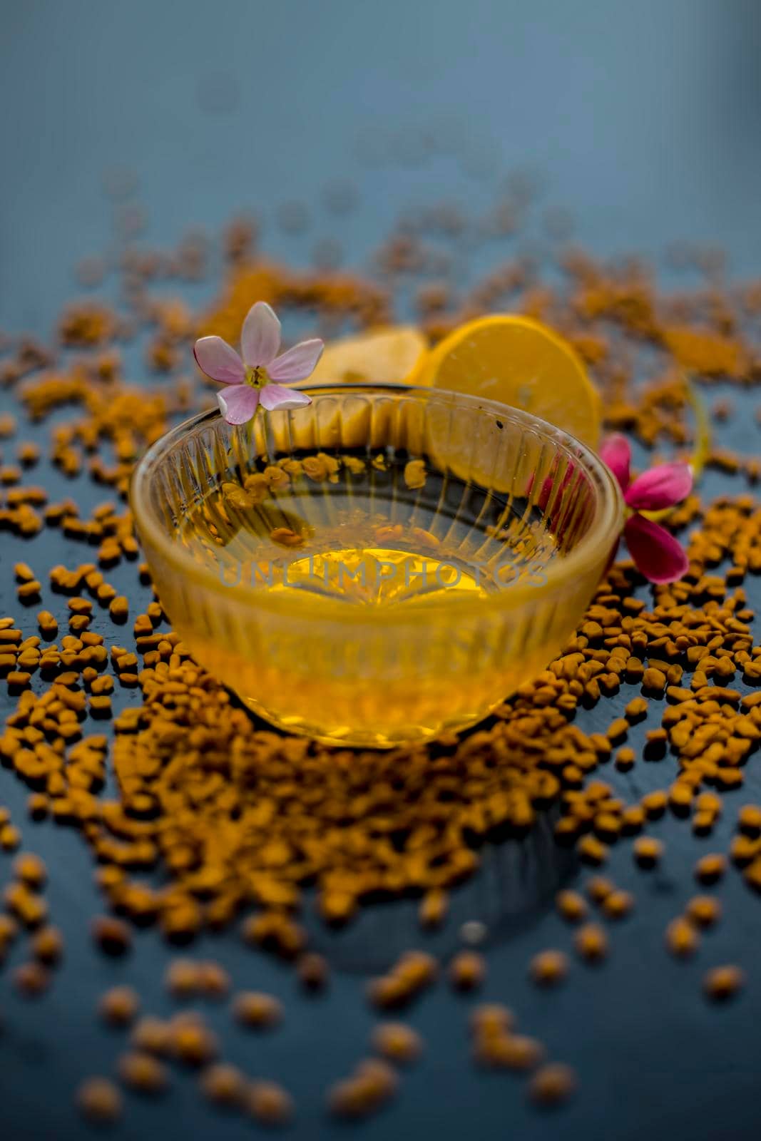 Famous natural method for dandruff on wooden surface in a glass bowl consisting of fenugreek seeds powder well mixed with lemon juice.With raw lemons and fenugreek seeds on the present on the surface. by mirzamlk