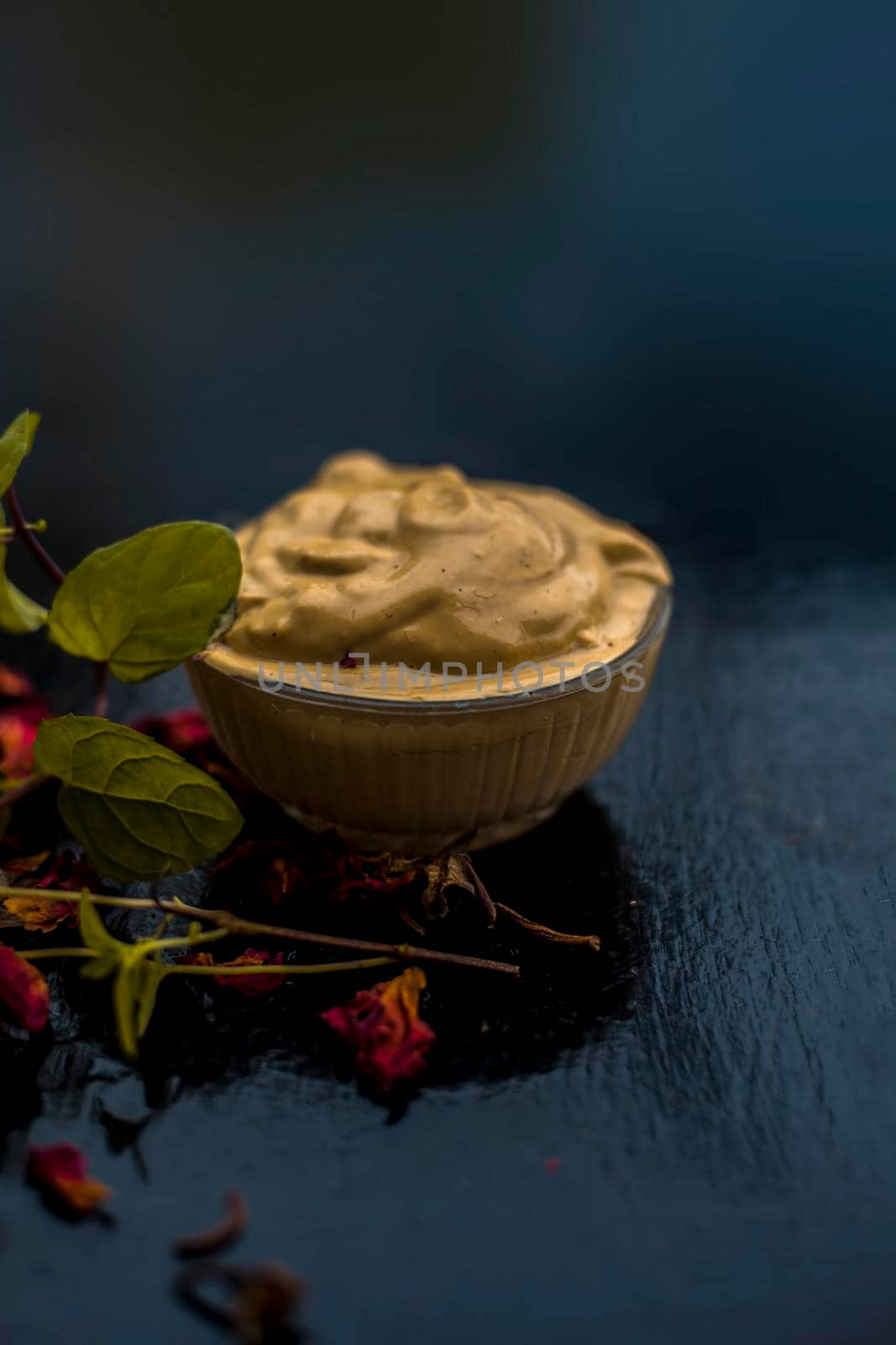 Homemade DIY face mask on the wooden surface consisting of yogurt,multani mitti or mulpani mitti (fuller's earth) and mint leaves in a glass bowl. For the treatment removal of dark patches.