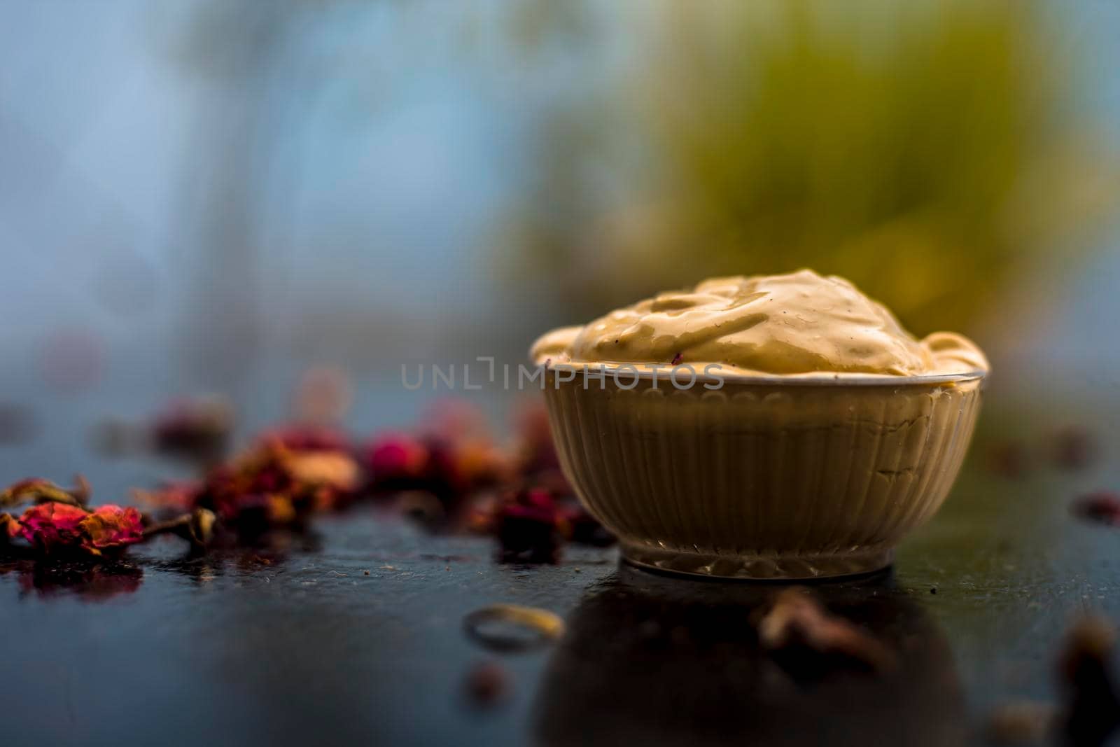 Ubtan/face mask/face pack of Multani mitti or fuller's earth on wooden surface in a glass bowl consisting of Multani mitti and rose water for the remedy or treatment of oily skin.On wooden surface.