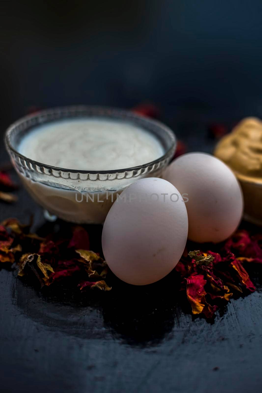 Best DIY face mask of multani mitti or mulpani mitti along with egg white and some yogurt well mixed in a glass bowl on the black wooden surface for the remedy of even skin.