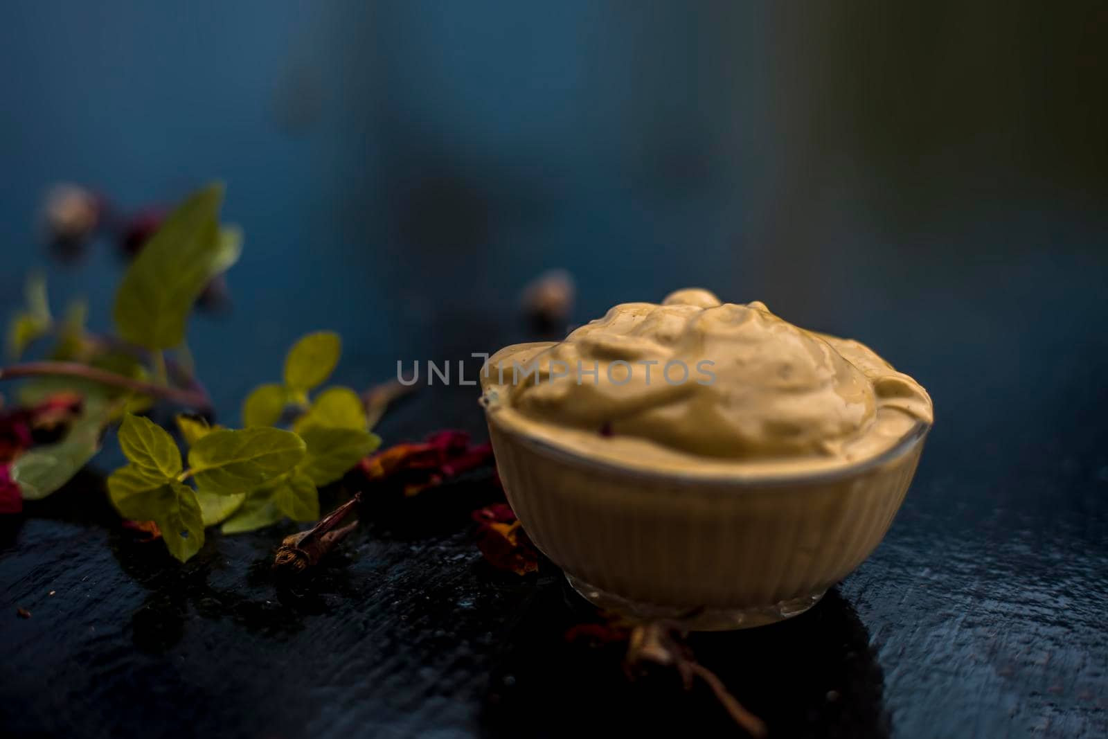Homemade DIY face mask on the wooden surface consisting of yogurt,multani mitti or mulpani mitti (fuller's earth) and mint leaves in a glass bowl. For the treatment removal of dark patches. by mirzamlk
