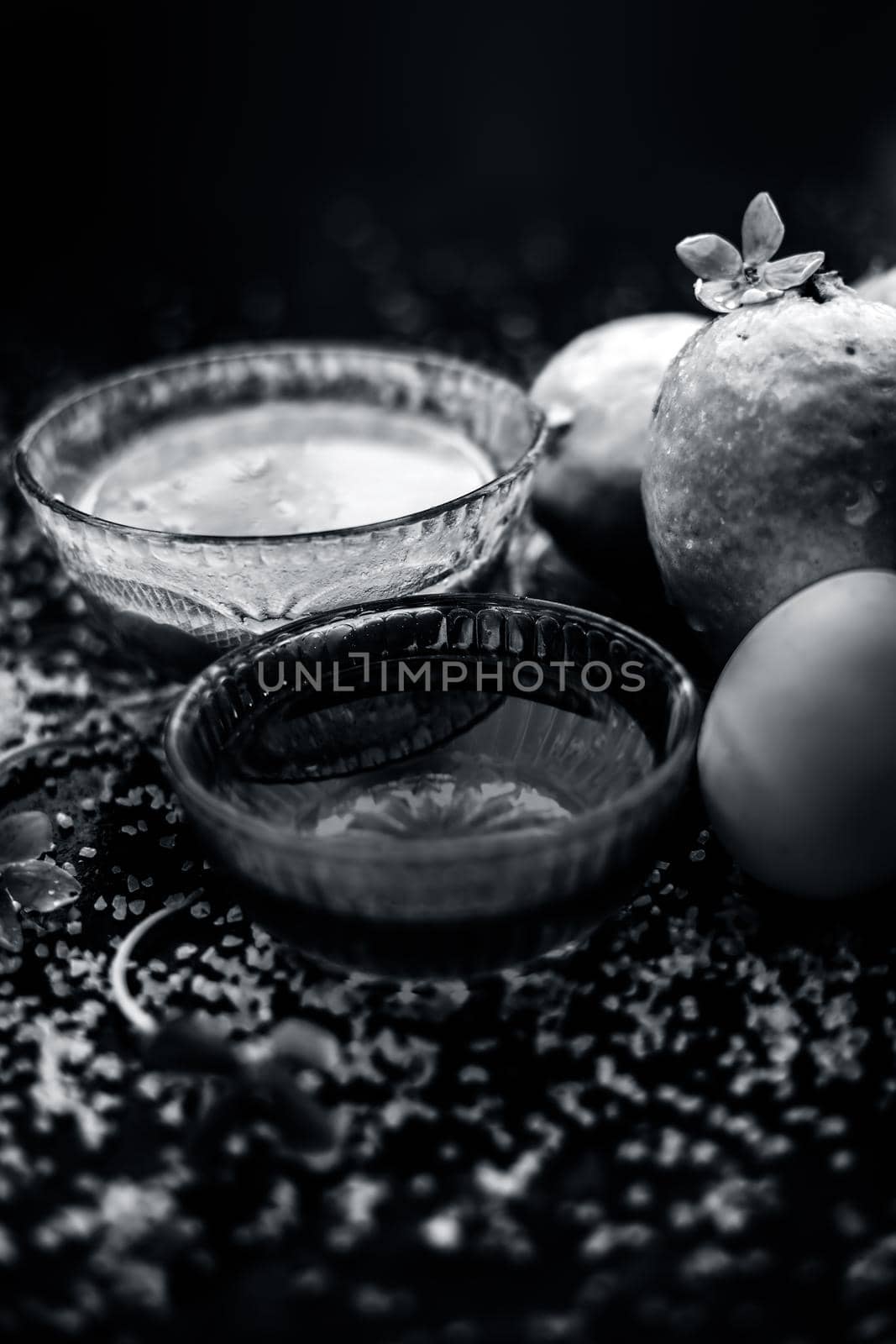 Treatment of dry skin with the help of face mask on a wooden surface consisting of honey, guava pulp, egg yolk, and some oatmeal, well mixed in a glass bowl along with raw ingredients.