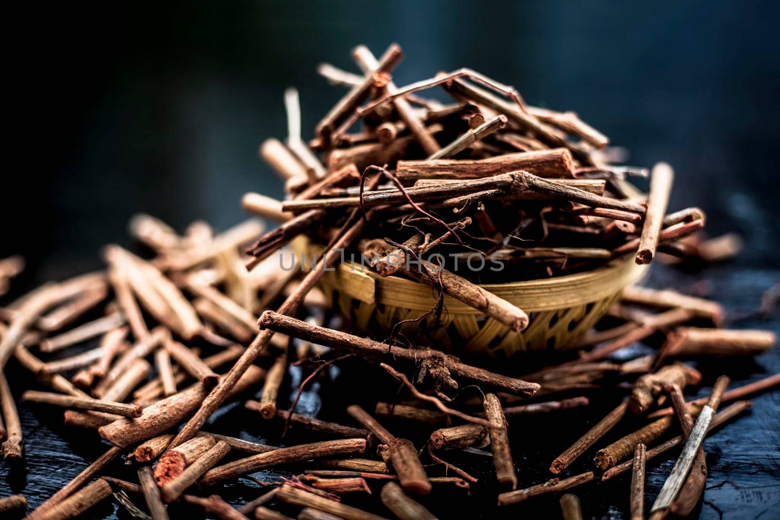 Bunch of Indian madderwort or madder root in a brown-colored basket on the black wooden surface also known as manjistha/manzistha/Rubia cordifolia/madder etc. by mirzamlk