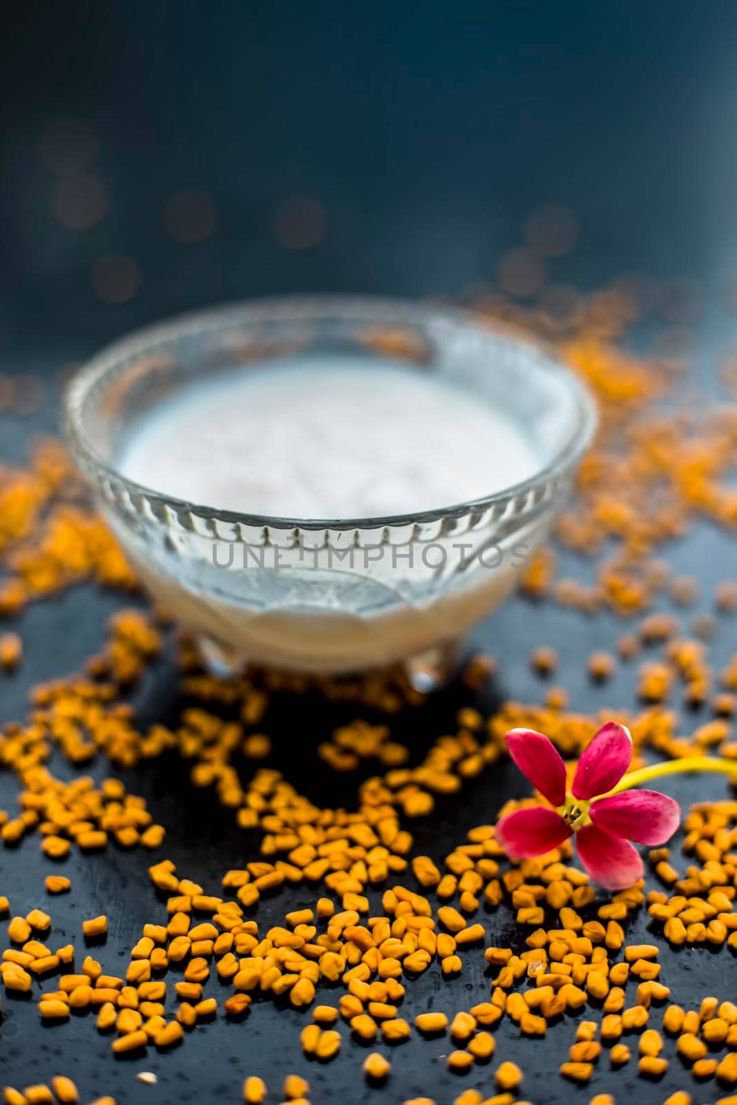 A famous natural method for dandruff on wooden surface in a glass bowl consisting of fenugreek seeds powder well-mixed with curd in a glass bowl.Along with raw curd and fenugreek seeds on the surface. by mirzamlk