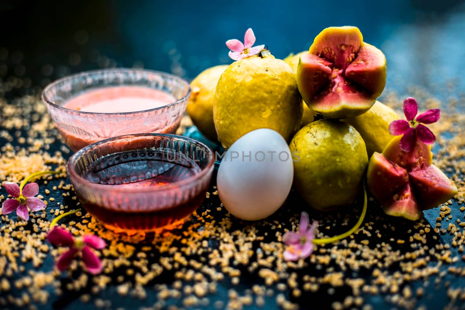 Treatment of dry skin with the help of face mask on a wooden surface consisting of honey, guava pulp, egg yolk, and some oatmeal, well mixed in a glass bowl along with raw ingredients. by mirzamlk