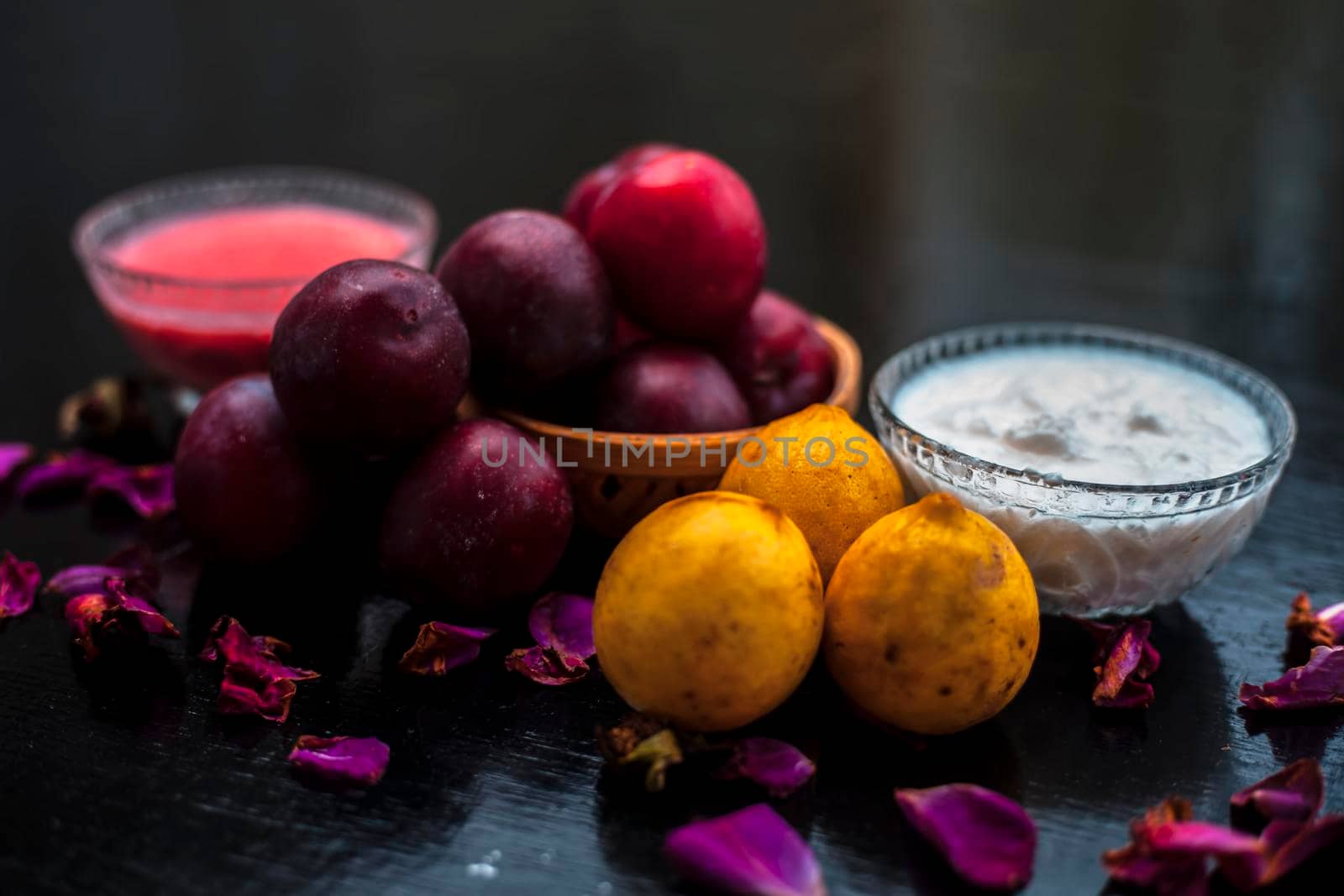 Healthy face mask of plum or aloo Bukhara in a glass bowl on the wooden surface consisting of plum extract, water, curd, and some lemons also for protection against harmful UV rays and sun damage.
