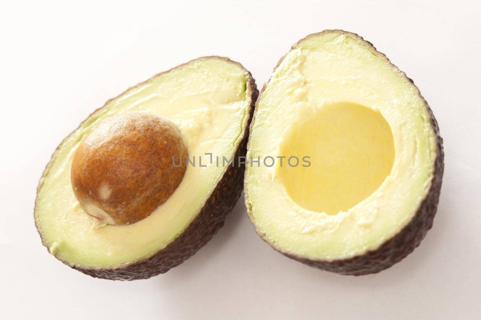 Avocado fruit sliced open to reveal the tasty flesh and large pip for a delicious salad ingredient in vegetarian and vegan cuisine