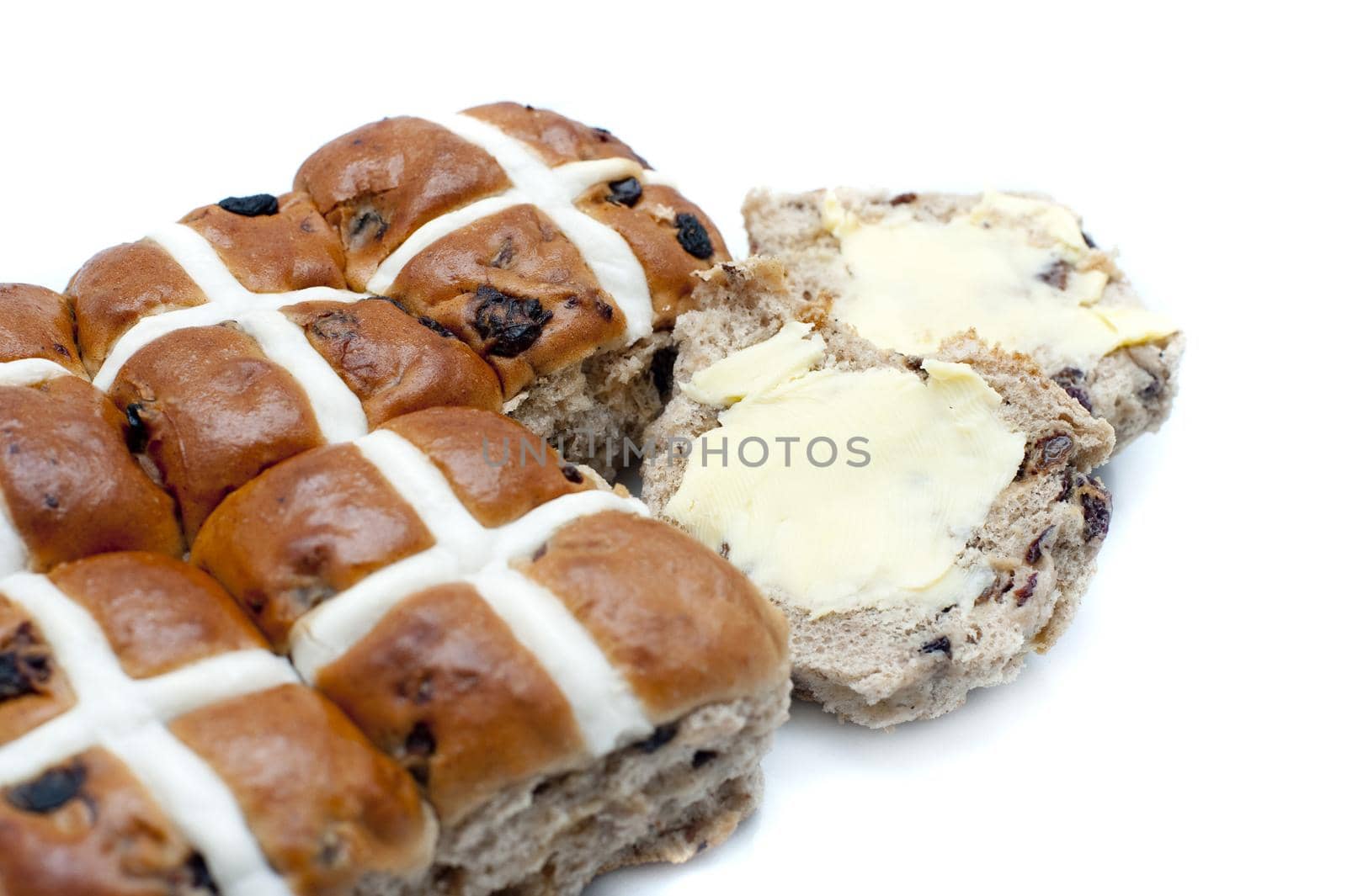 Batch of spicy Easter Hot Cross Buns with one sliced and buttered ready to eat