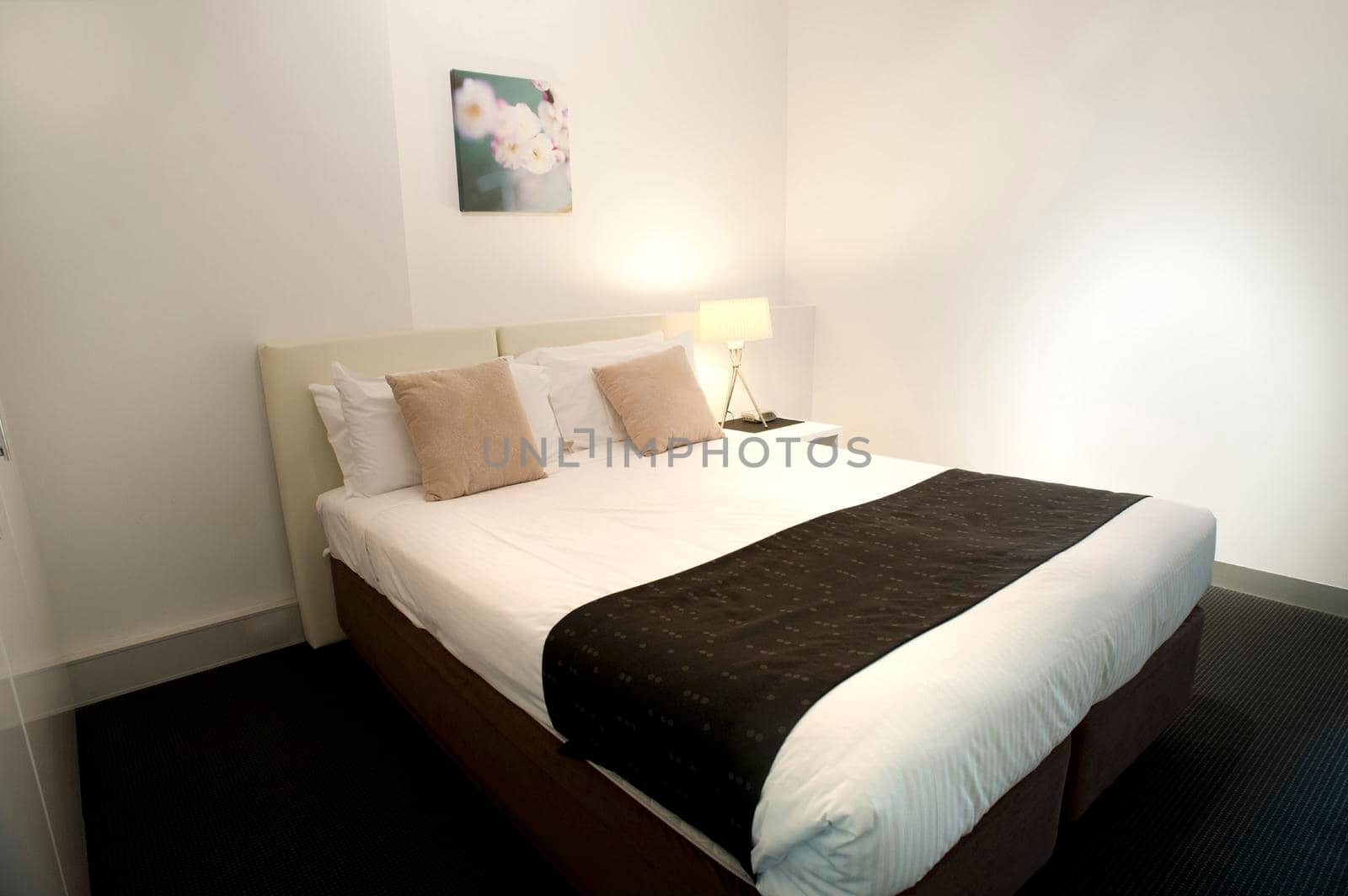 Contemporary bedroom interior with a comfortable double bed and minimalist decor in neutral colours with black accents