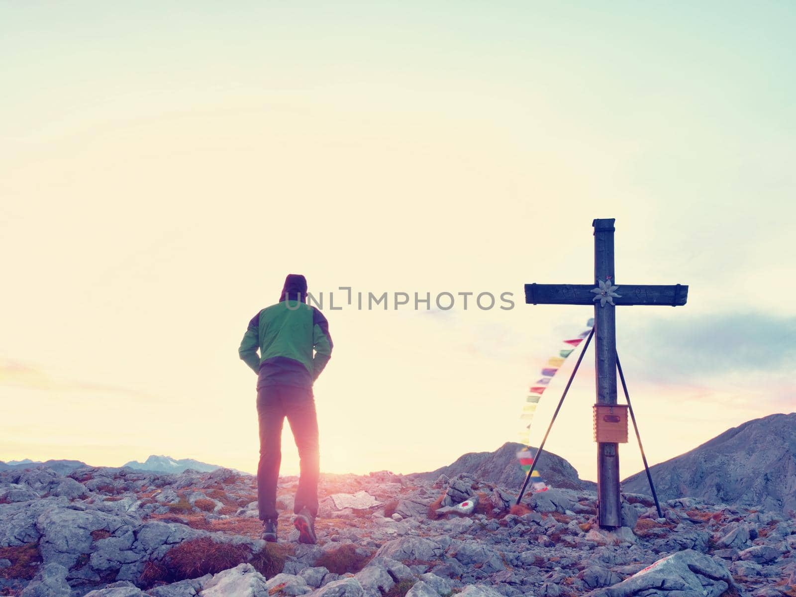 Alone man climber near the summit cross on peak, Dolomite Alps, Austria. Sunny windy evening, great visibility