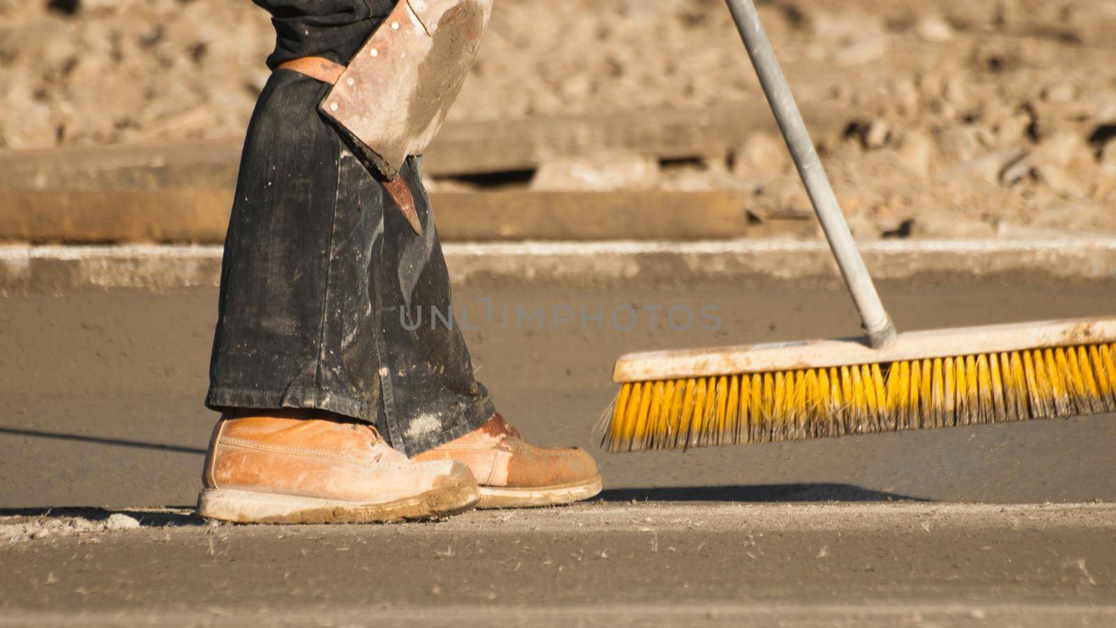 Construction worker leveling a new cement road.