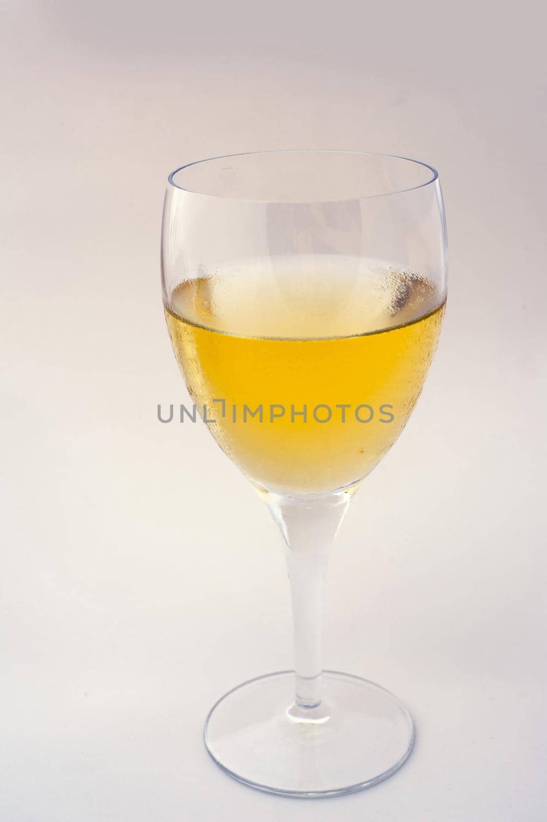 Close up side view of a single glass of white wine over a grey studio background with copyspace