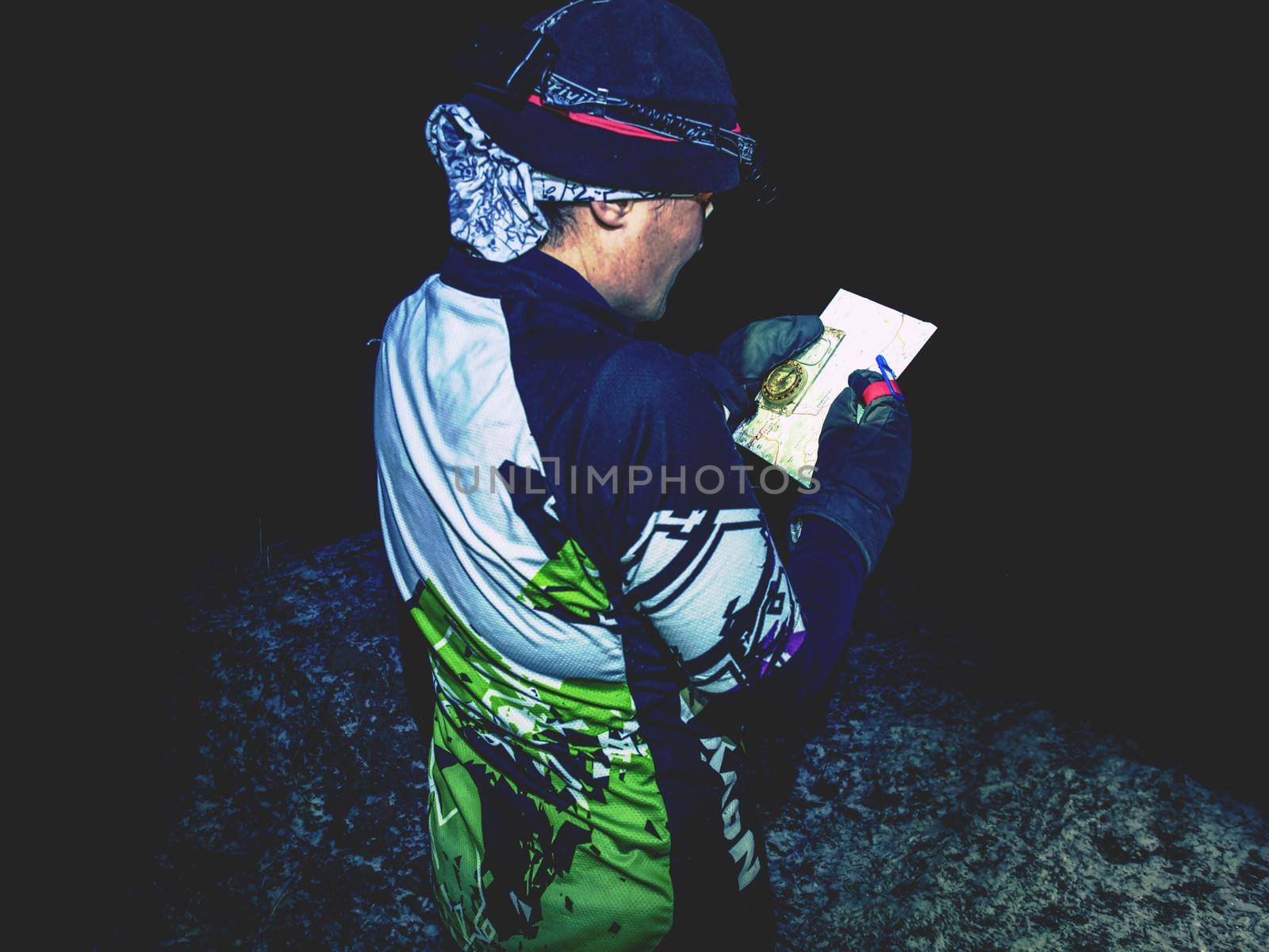 Winter night extreme runner control map.  January 25th 2019, Novy Bor, Czech Republic. Girl in forest reading map and checking a control point. Selective focus