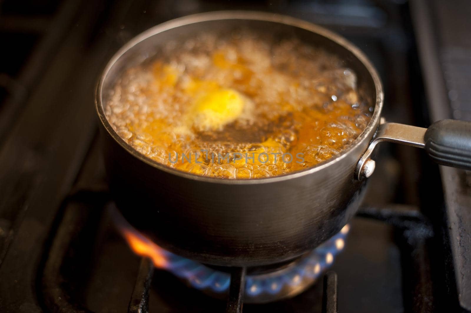 Fresh diced pumpkin boiling in a pot over a gas hob in the kitchen during cooking for the evening meal