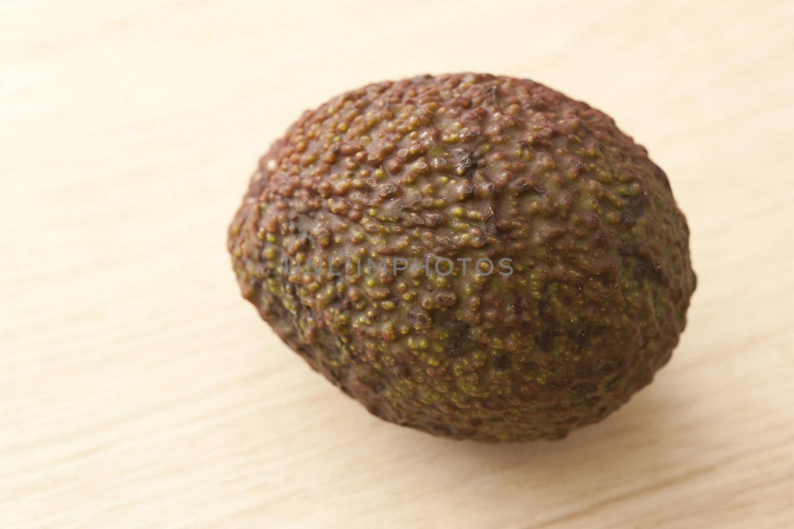 Close Up Still Life of Single Avocado with Textured Skin on Wooden Background with Copy Space