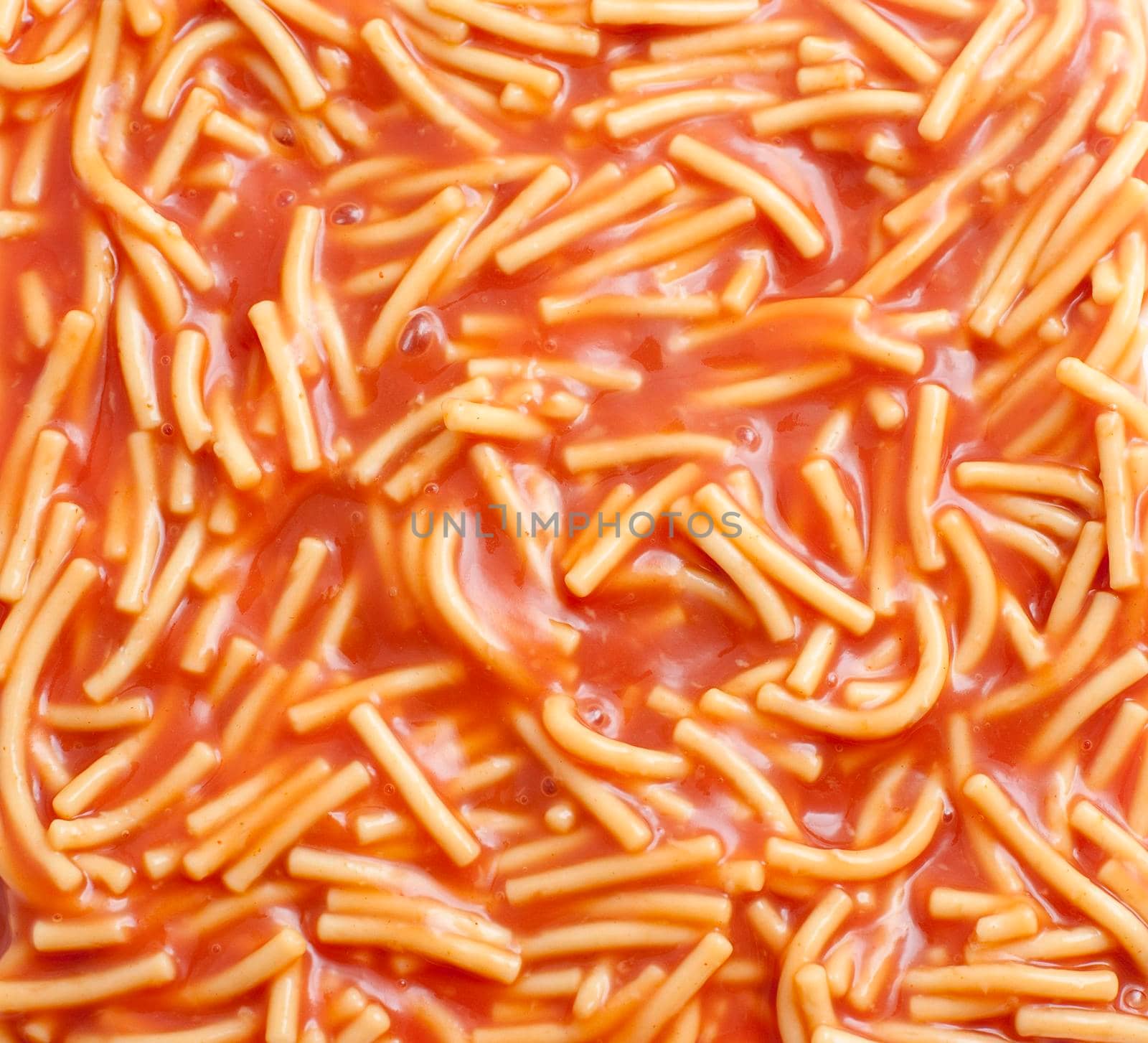 Background of canned spaghetti or noodles in tomato sauce, a quick snack and a favourite of children