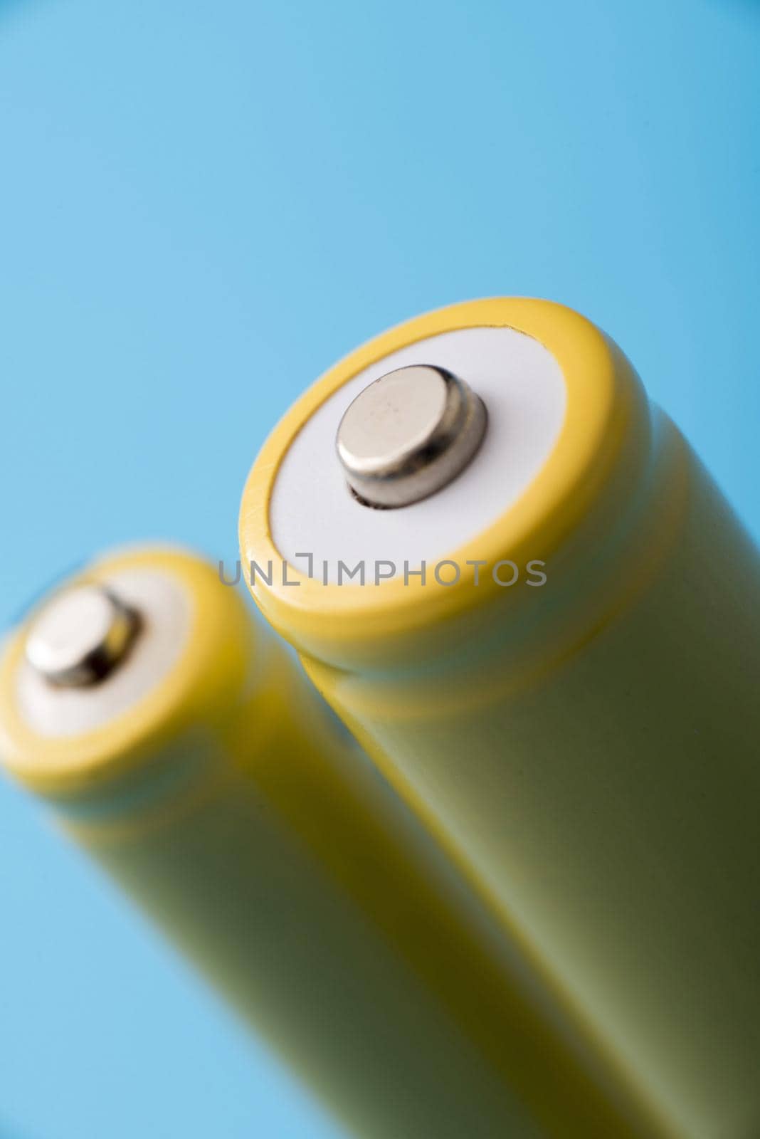 Close up view of the positive terminal on a rechargeable battery over a blue background in a power and energy concept