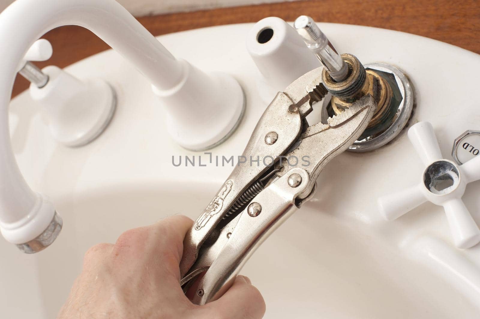 Man repairing a faucet with a mole grip by sanisra