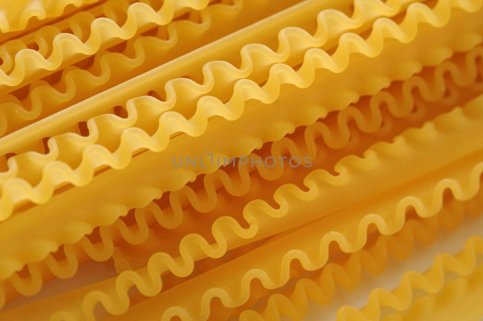 Background Close Up of Frilled Edges of Dry Lasagna Noodles - Arranged in Diagonal Pattern Across Frame