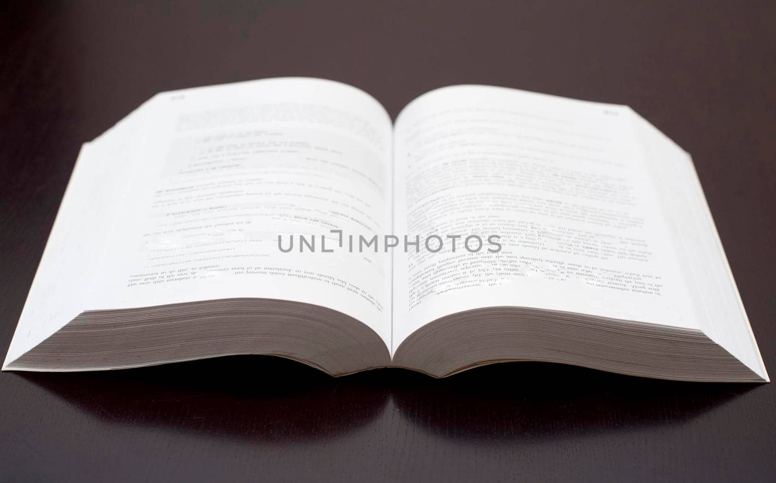 A studio shot of an open paperback book over a black background