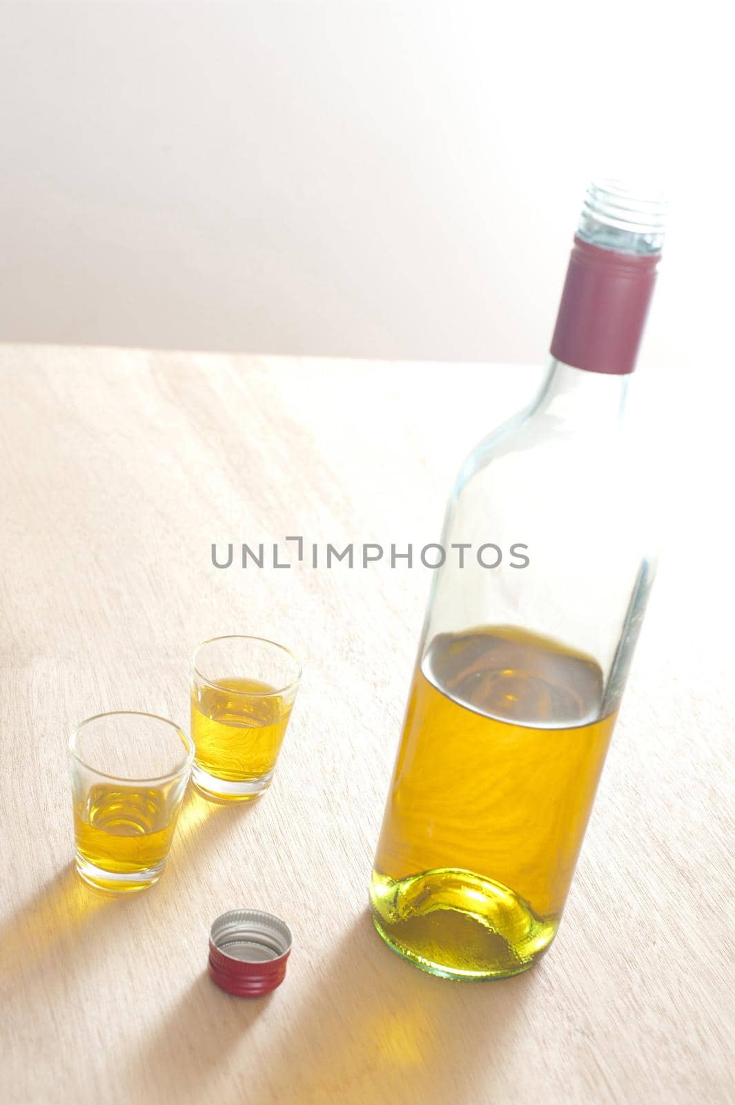 Close up Unlabled Bottle and Glasses of Yellow Wine on Top of a Wooden Table