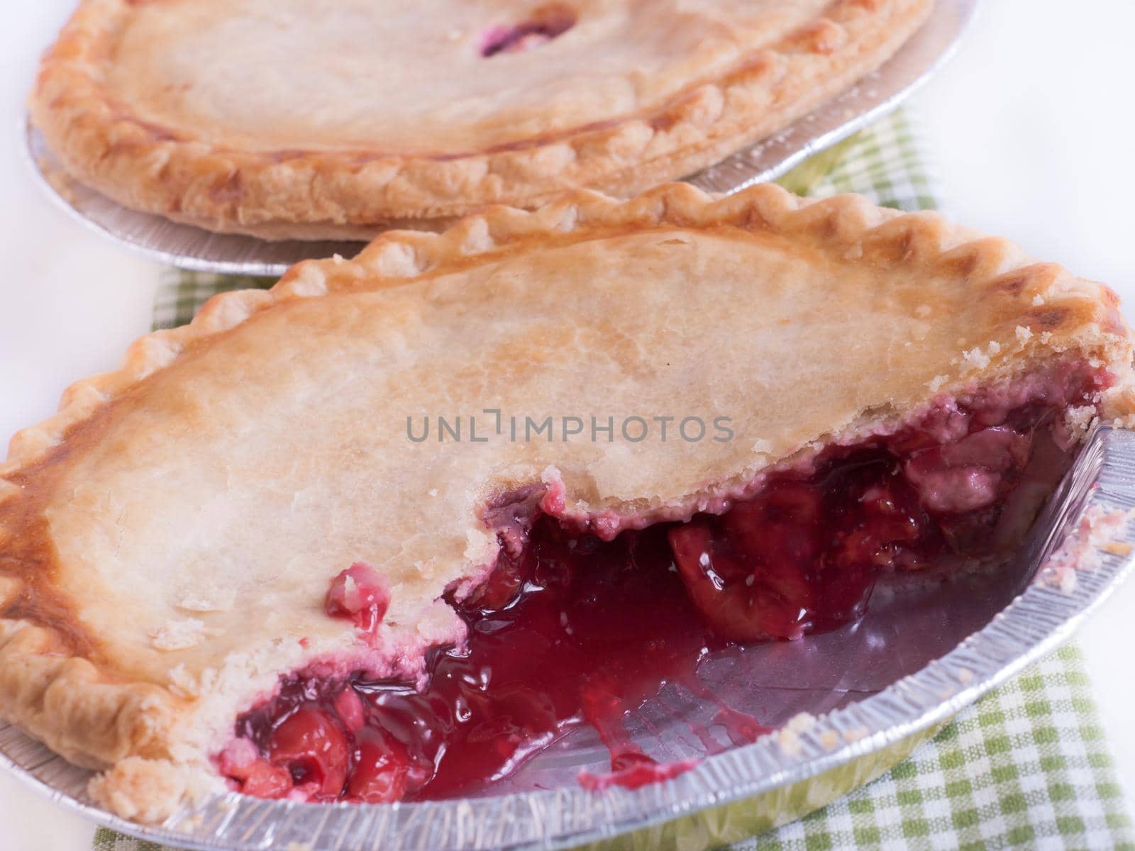 Cherry pie in baking tin with piece missing.