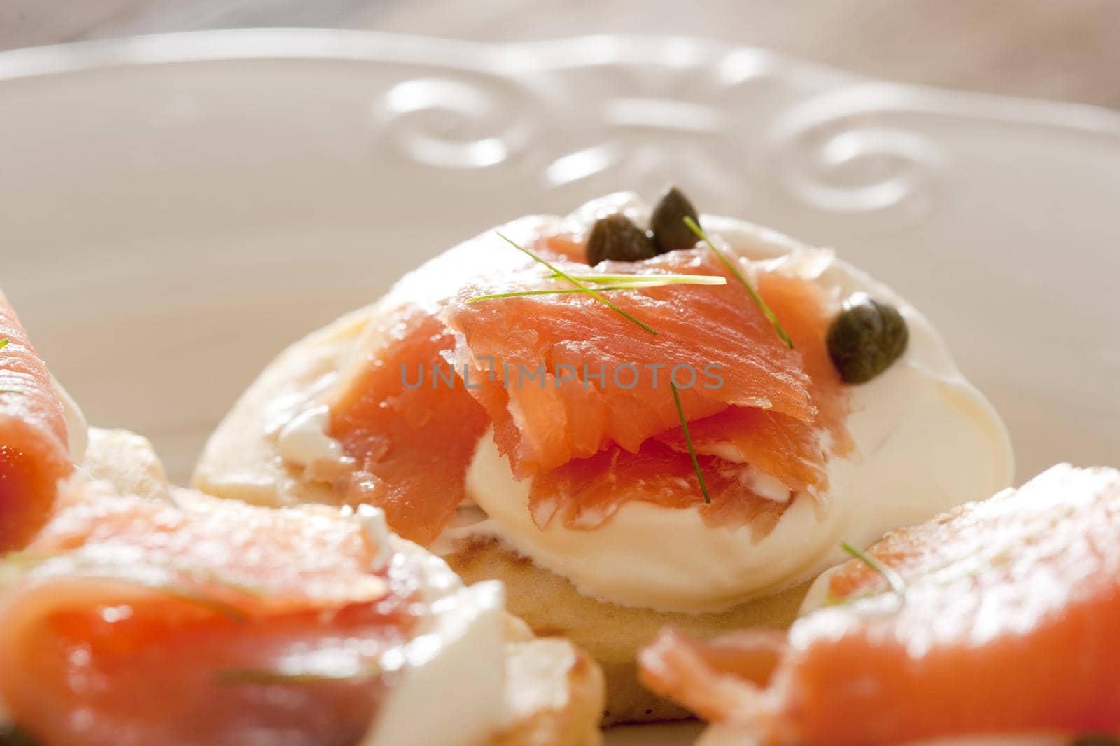 Delicious snacks or appetizers of fresh smoked salmon and capers on cream cheese served on sliced bread