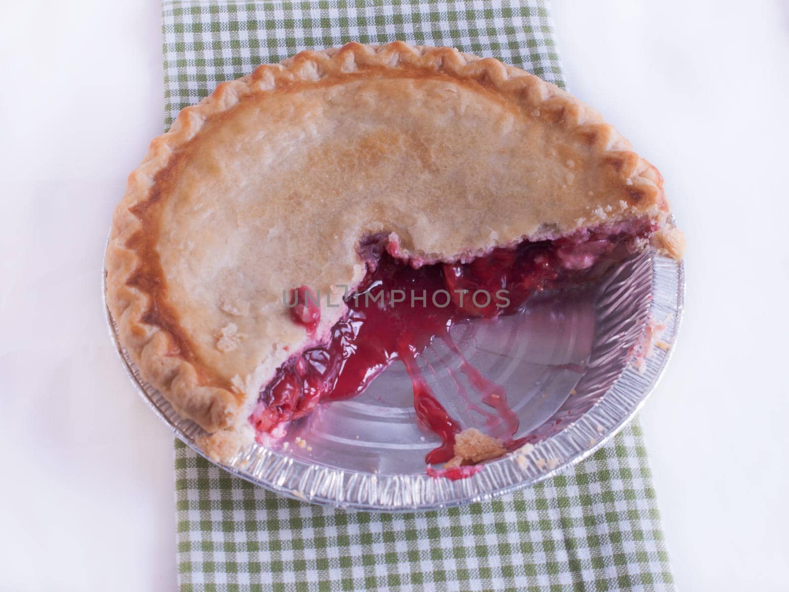Cherry pie in baking tin with piece missing.