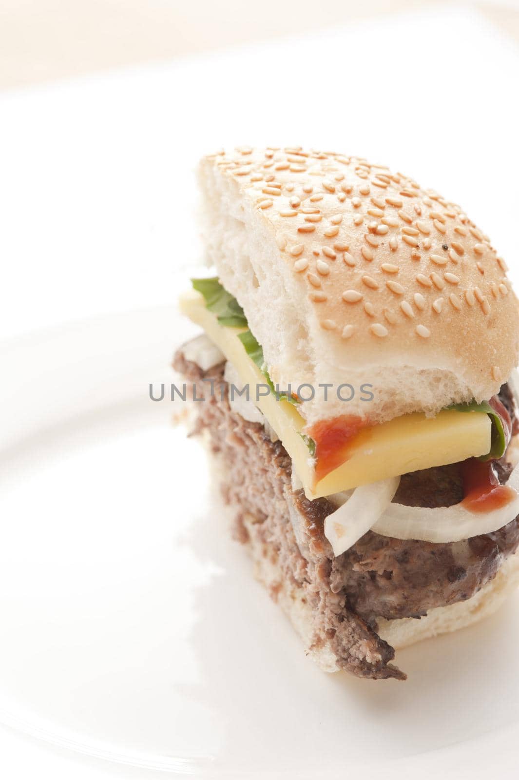 Half cut cheeseburger sliced through the center with a thick juicy beef patty and salad trimming s with a slice of cheese
