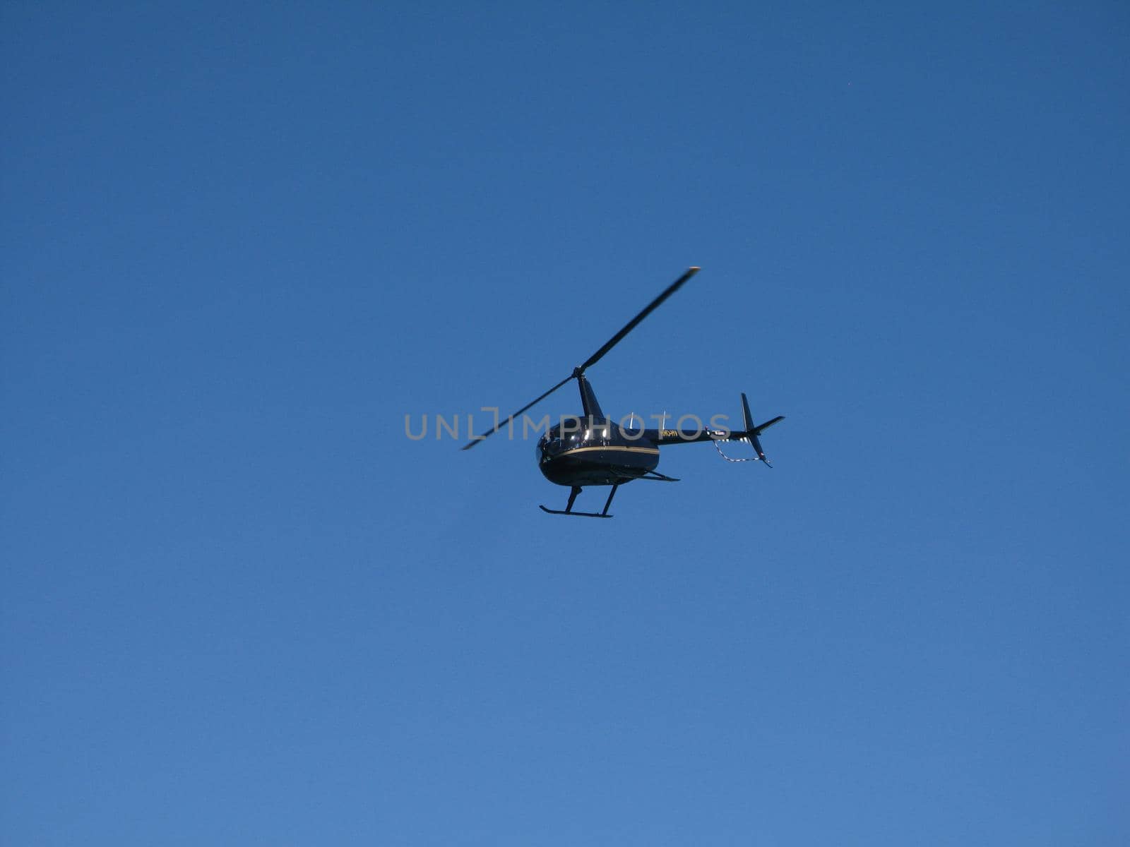 Black Helicopter Flying up in the Blue Gray Sky, Emphasizing Copy Space.