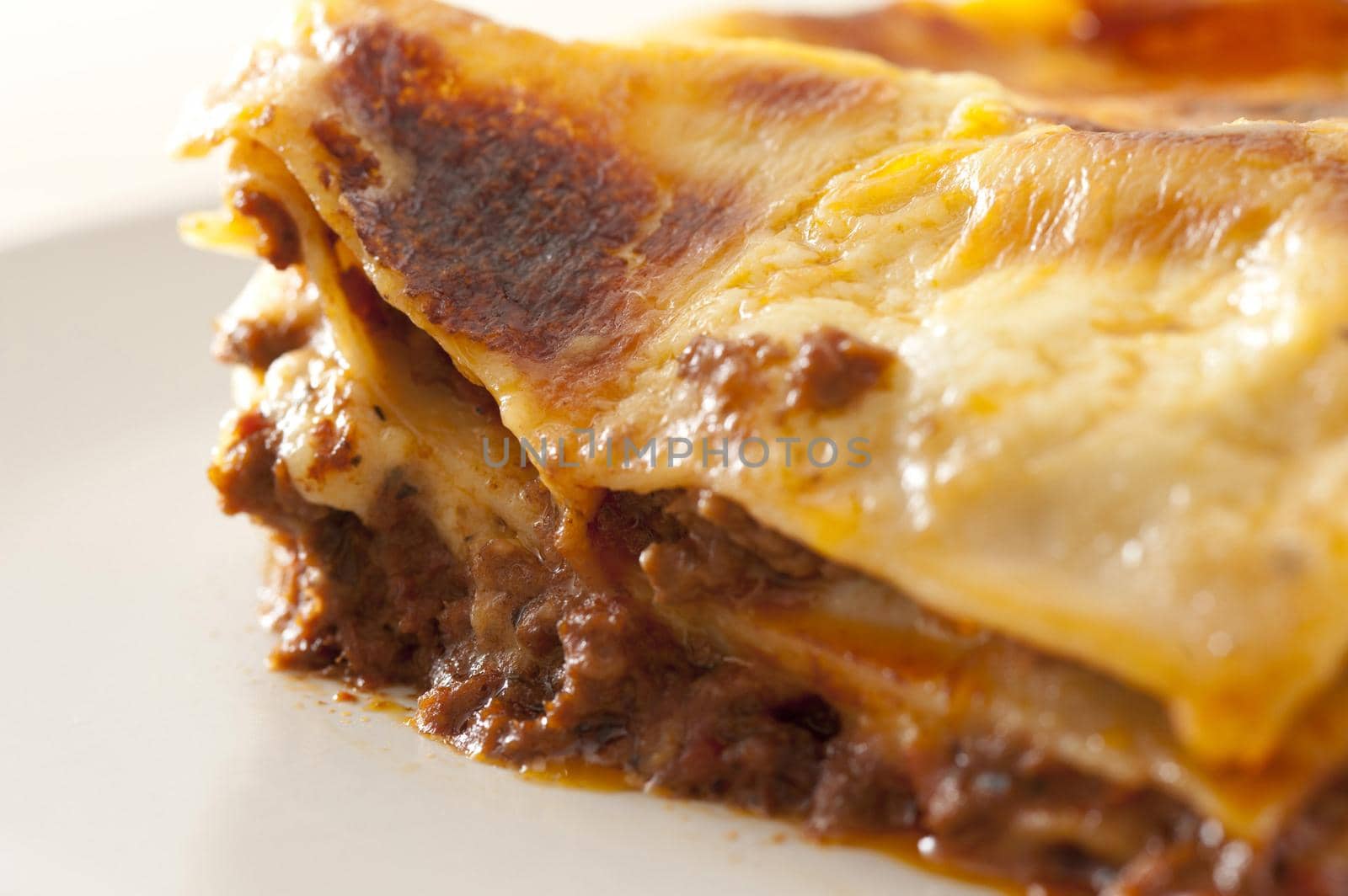 Close up Edge of Freshly Cooked Tasty Italian Lasagne Dish on a White Plate.