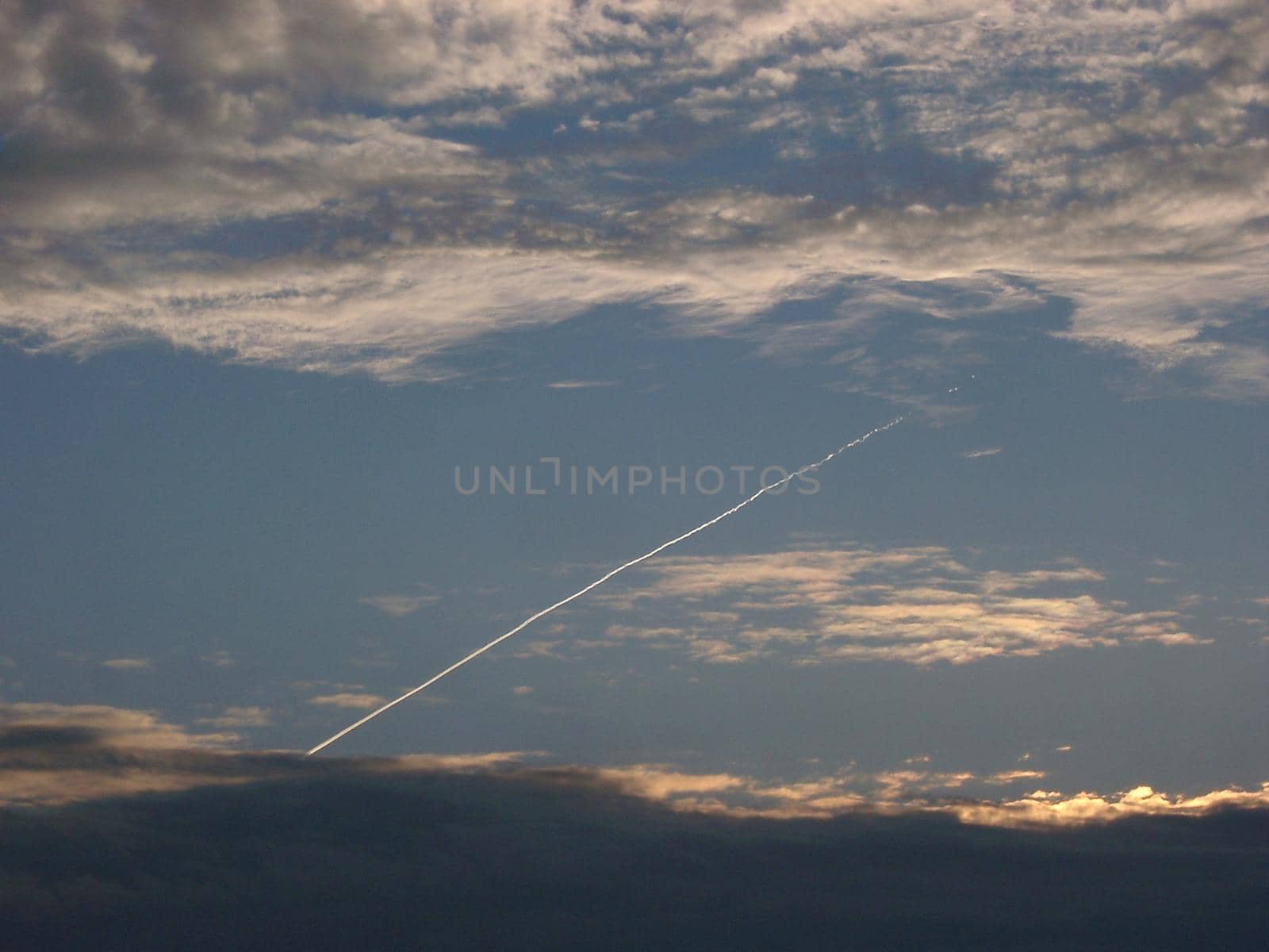 clouds and sky with a vapour trail from a passing jet aircraft
