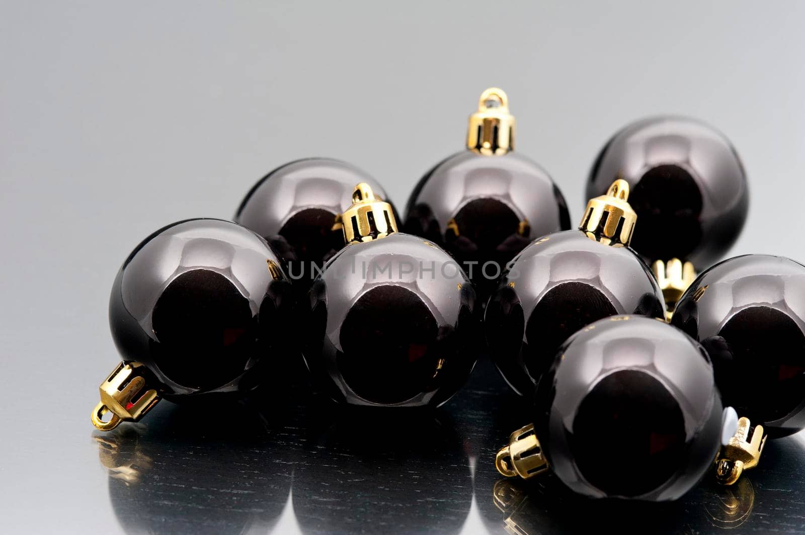 Collection of shiny black Christmas baubles on a reflective surface with copyspace