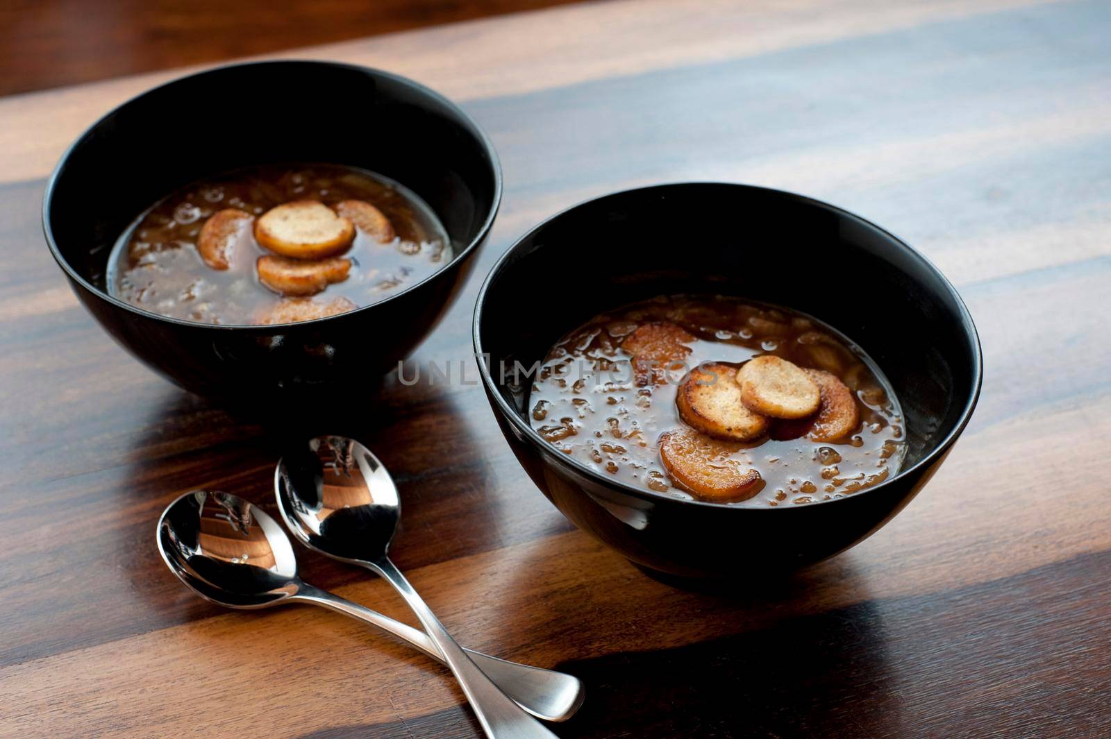 Two bowls of steaming hot french brown onion soup in bowls served as a starter and appetizer on a cold winter day