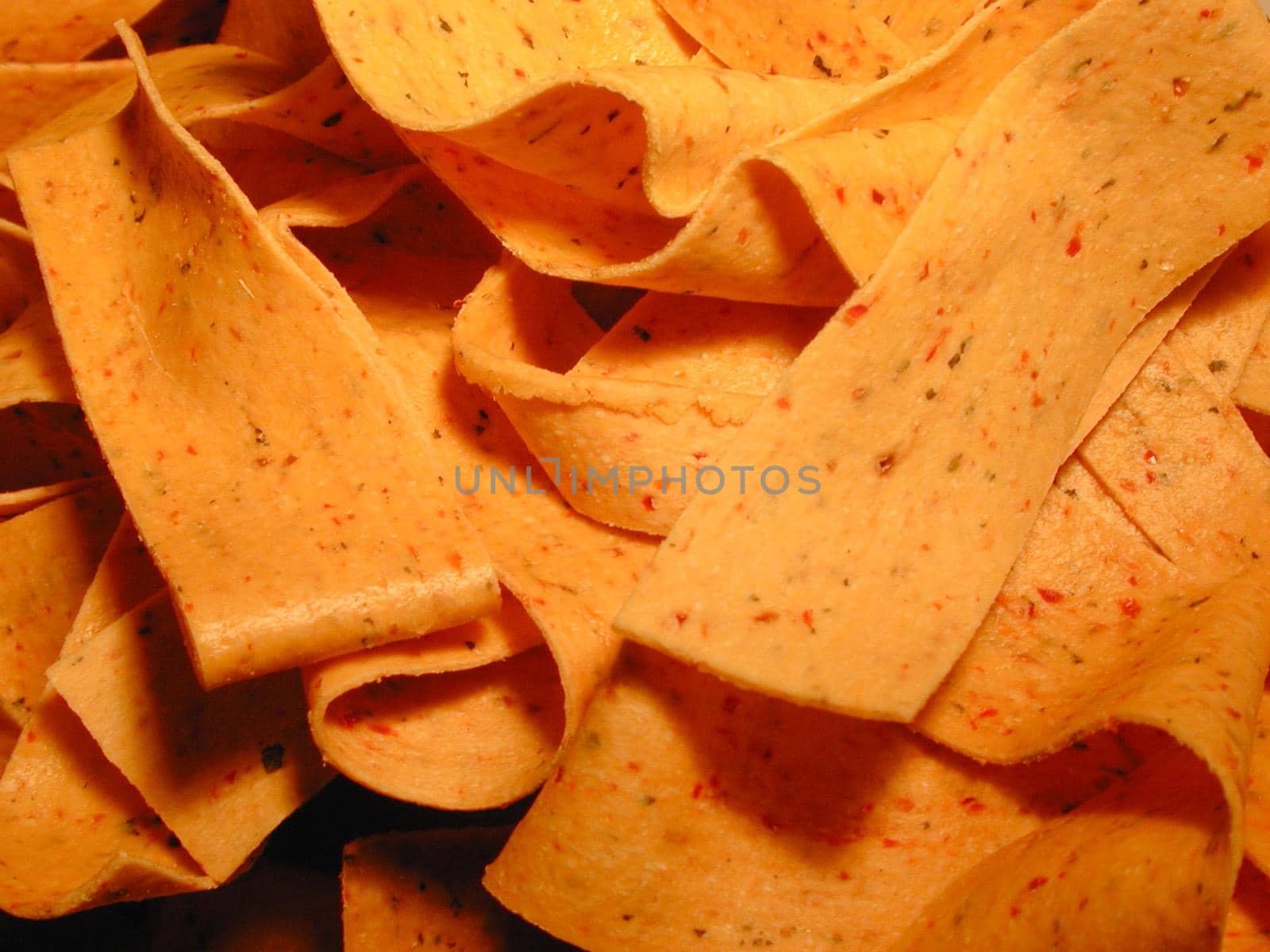 Seasoned Italian pasta ribbons or noodles in a full frame background texture in warm light