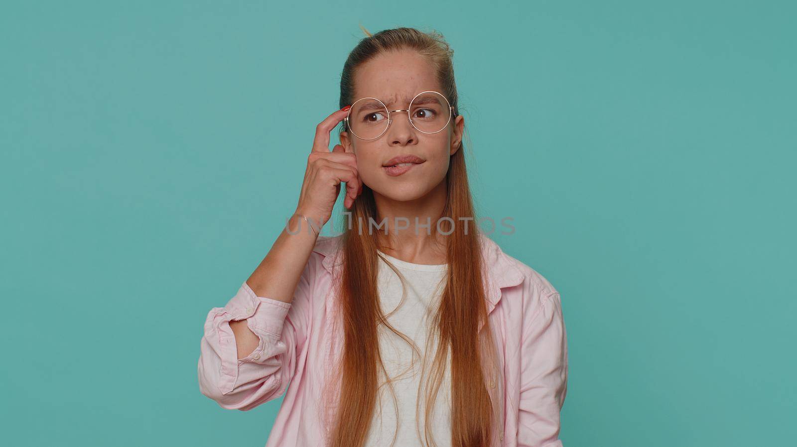 I dont know what to say. Confused pretty teenager young girl feeling embarrassed about ambiguous question, having doubts, no idea, being clueless and uncertain. Student child kid on blue background