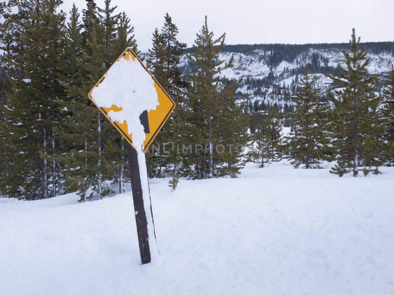 Yellow road sign covered in snow at the Great Teton national park.