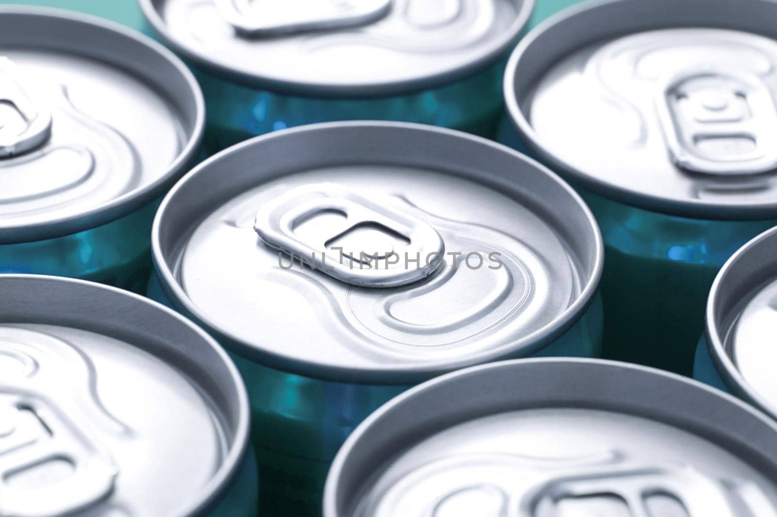 Close up view of plain silver ring pulls on closely arranged beverage cans with focus to one can in the centre