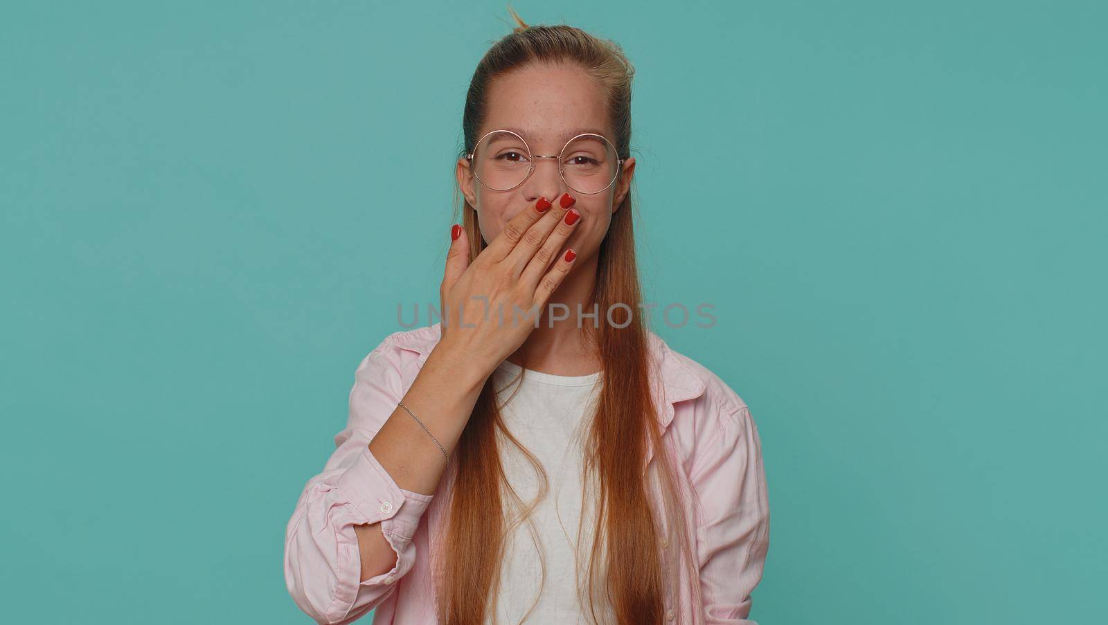 I will not say anyone. Frightened teen girl closing her mouth with hand, looking intimidated scared at camera, gestures no, refusing to tell terrible secret, unbelievable truth. Young female child kid